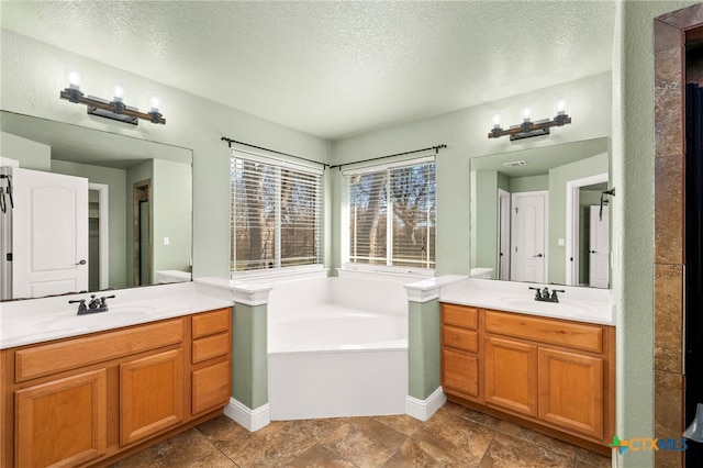 bathroom featuring a tub to relax in, a textured ceiling, and vanity