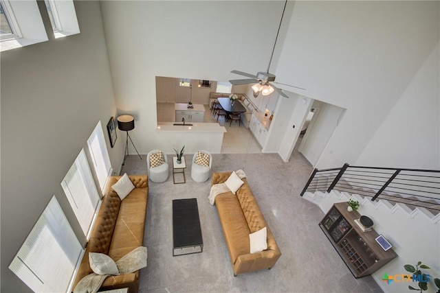 living room featuring ceiling fan, a towering ceiling, and a healthy amount of sunlight