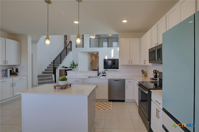 kitchen with appliances with stainless steel finishes, sink, decorative light fixtures, a center island, and white cabinetry