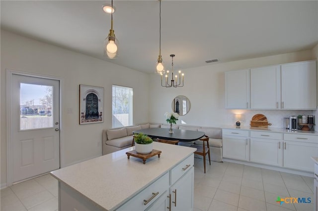 kitchen with a center island, an inviting chandelier, backsplash, pendant lighting, and white cabinets