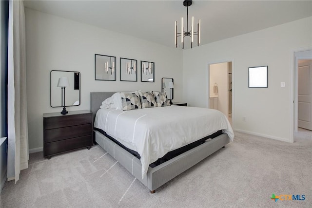 bedroom featuring an inviting chandelier, light colored carpet, and ensuite bath