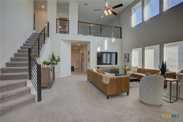 carpeted living room with a high ceiling and ceiling fan