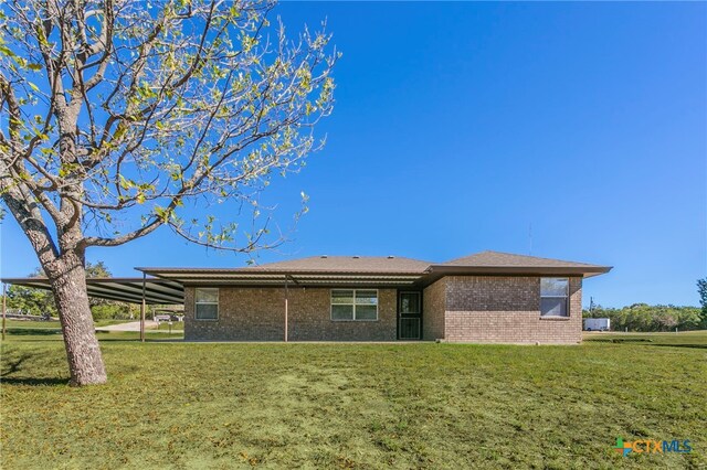 back of property with a lawn and a carport