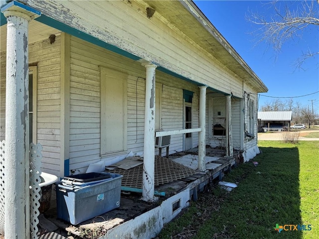 view of exterior entry with covered porch and a yard