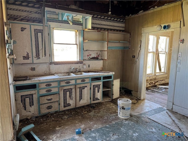 kitchen featuring tile countertops, open shelves, and a sink