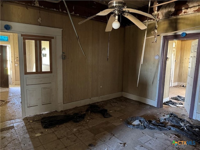 empty room with wood walls and a ceiling fan