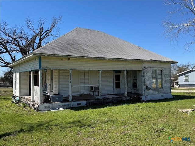 rear view of house with a porch, a lawn, and a shingled roof