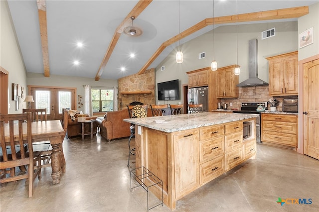 kitchen featuring pendant lighting, wall chimney range hood, stainless steel appliances, a center island, and a kitchen bar