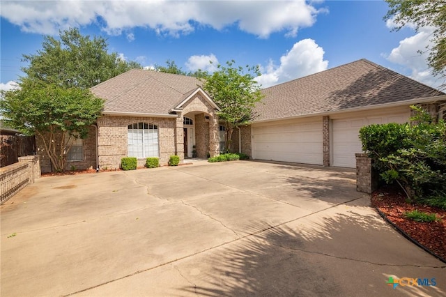 ranch-style house with fence, a shingled roof, driveway, brick siding, and a garage