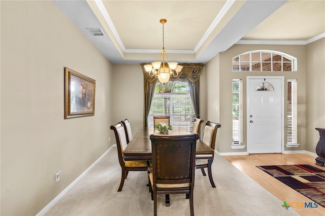 dining room with ornamental molding, a tray ceiling, a chandelier, and visible vents