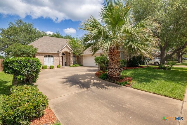 view of front of home with concrete driveway, a front lawn, brick siding, and a garage