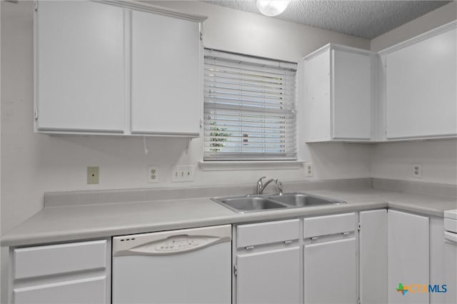 kitchen with light countertops, a textured ceiling, white cabinets, a sink, and dishwasher