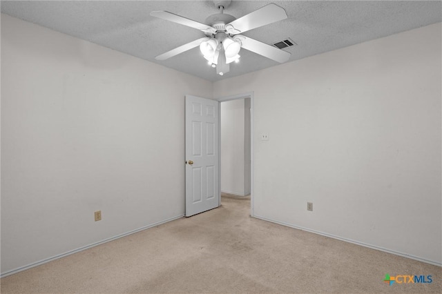 empty room with a ceiling fan, a textured ceiling, visible vents, baseboards, and light carpet
