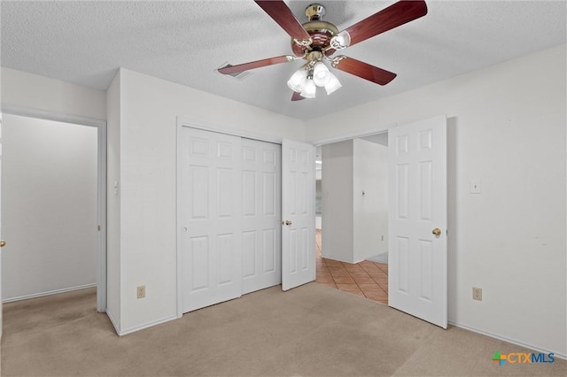 unfurnished bedroom with a closet, a ceiling fan, carpet, and a textured ceiling