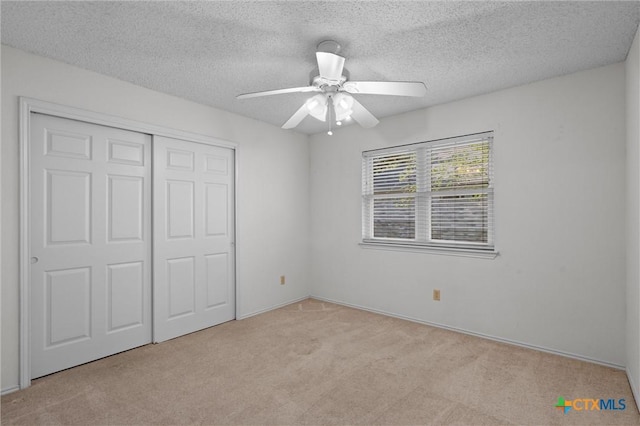 unfurnished bedroom with a closet, a textured ceiling, carpet, and ceiling fan