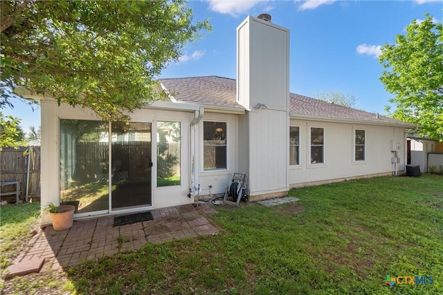 back of property with fence, roof with shingles, a chimney, central air condition unit, and a yard
