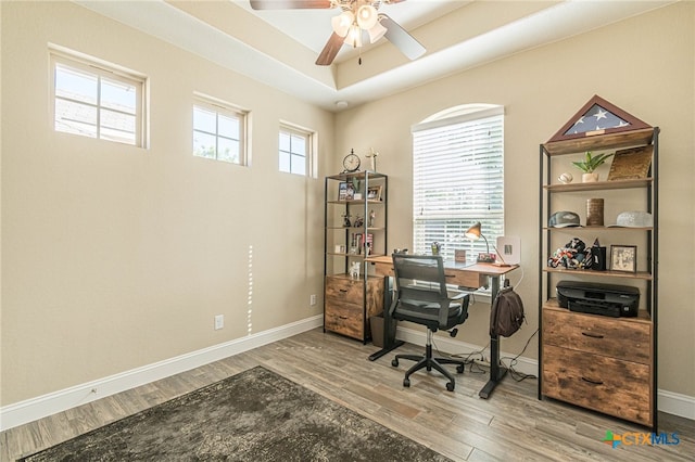 office area with hardwood / wood-style flooring, ceiling fan, and a raised ceiling