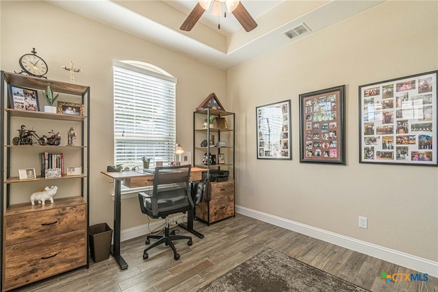 office space featuring a raised ceiling, ceiling fan, and hardwood / wood-style flooring