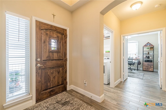 foyer entrance featuring plenty of natural light, washer / dryer, and light wood-type flooring