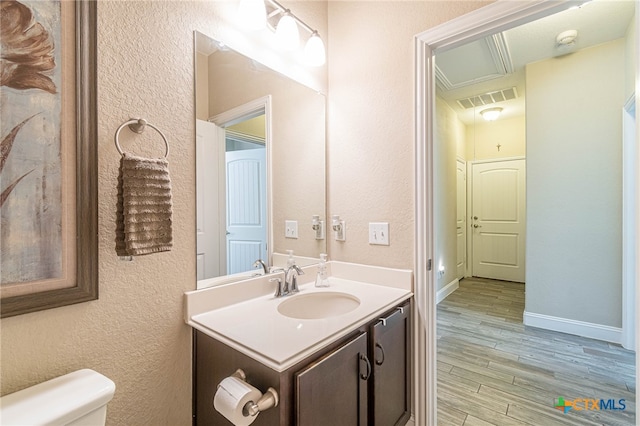 bathroom with toilet, vanity, and hardwood / wood-style flooring