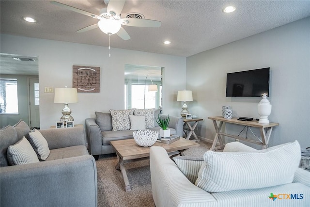 living room featuring ceiling fan, carpet flooring, and a textured ceiling