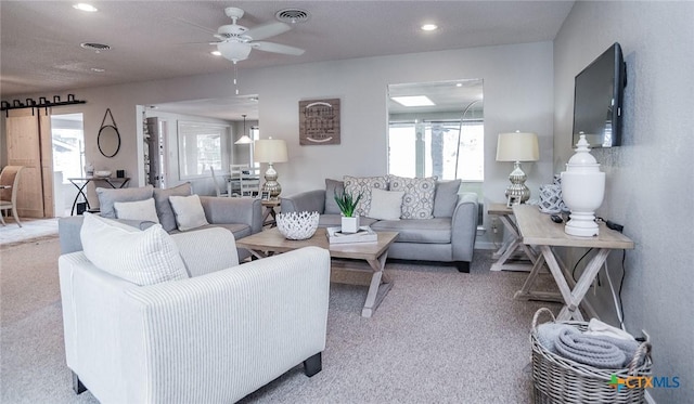 living room with a barn door, light carpet, and ceiling fan