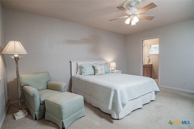 bedroom featuring ceiling fan, connected bathroom, light carpet, and a textured ceiling