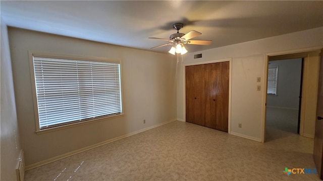 unfurnished bedroom featuring a closet, ceiling fan, baseboards, and visible vents