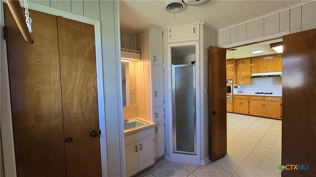 bathroom featuring a shower stall, ornamental molding, visible vents, wood walls, and tile patterned floors