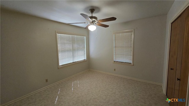 carpeted spare room with ceiling fan and baseboards