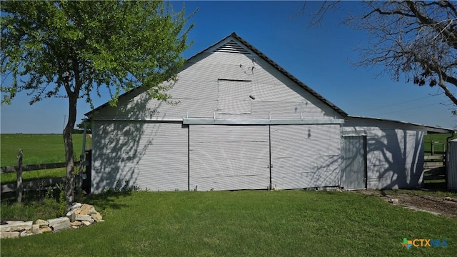 view of side of property featuring an outbuilding, fence, a barn, and a yard