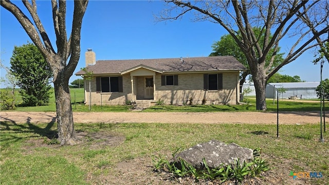 view of front of home featuring a front yard, brick siding, entry steps, and a chimney