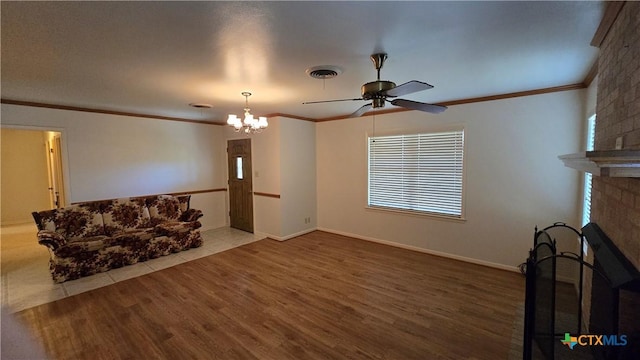living area with visible vents, ceiling fan with notable chandelier, ornamental molding, and wood finished floors