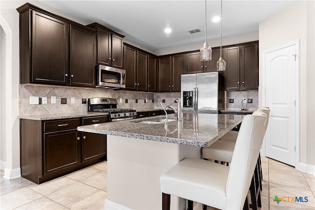 kitchen featuring sink, tasteful backsplash, a kitchen breakfast bar, dark brown cabinets, and appliances with stainless steel finishes