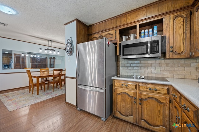 3909 Alderwood Ln, Temple, TX 76502 - kitchen featuring stainless steel appliances, brown cabinetry, a textured ceiling, decorative backsplash, and light countertops