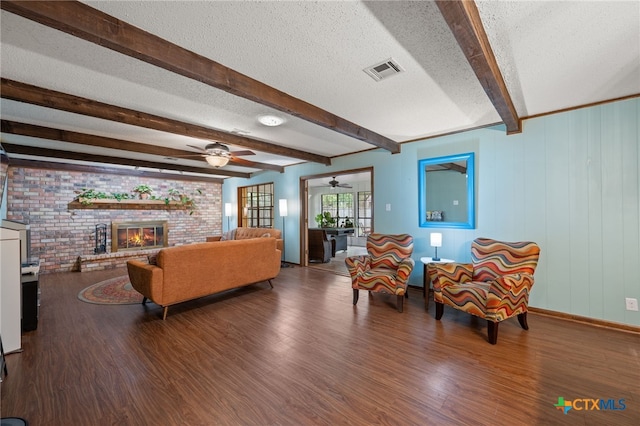 3909 Alderwood Ln, Temple, TX 76502 - living room with wood finished floors, beamed ceiling, a ceiling fan, a textured ceiling, and brick wall