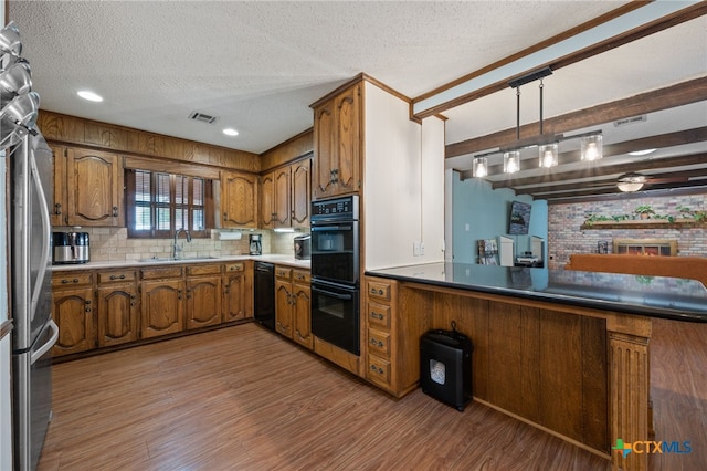 3909 Alderwood Ln, Temple, TX 76502 - kitchen featuring black appliances, a sink, brown cabinetry, a textured ceiling, and light wood finished floors