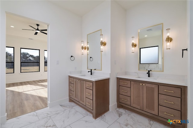 bathroom featuring marble finish floor, a ceiling fan, a sink, and two vanities