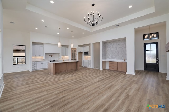 kitchen with open floor plan, an inviting chandelier, backsplash, and a raised ceiling
