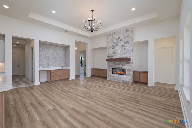 unfurnished living room with a tray ceiling and light wood-type flooring