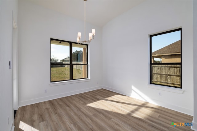 unfurnished dining area featuring baseboards, lofted ceiling, wood finished floors, and a notable chandelier