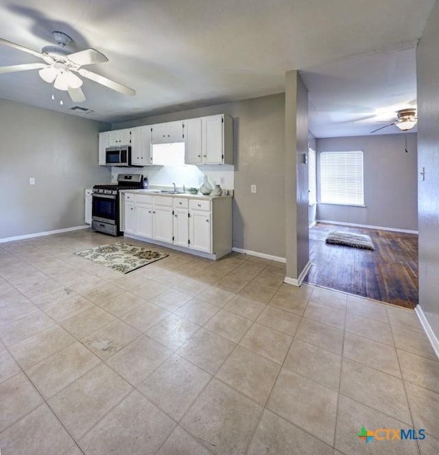 3207 Linda Dr, Victoria, TX 77901 - kitchen with appliances with stainless steel finishes, a ceiling fan, light tile patterned floors, white cabinetry, and light countertops