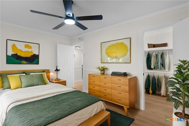 bedroom with light wood-style floors, visible vents, crown molding, and a ceiling fan
