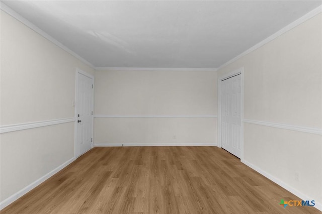 empty room with baseboards, crown molding, and wood finished floors