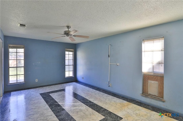 unfurnished room with ceiling fan and a textured ceiling