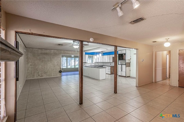 basement featuring ceiling fan, a textured ceiling, and light tile patterned floors