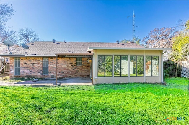 rear view of property with a yard, a patio, and a sunroom