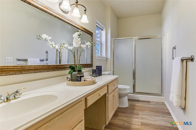 bathroom featuring hardwood / wood-style flooring, vanity, toilet, and a shower with shower door