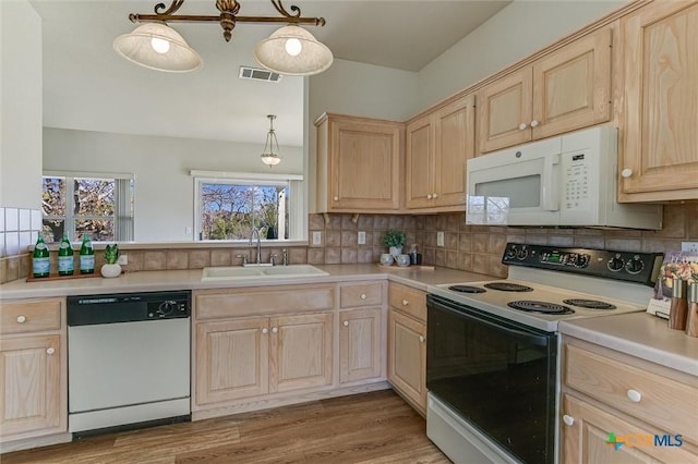 kitchen featuring white appliances, decorative light fixtures, light brown cabinetry, and sink