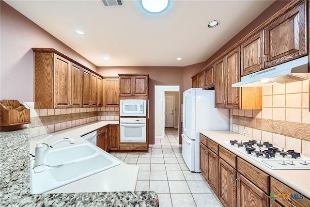 109 Ranch House Cv, Georgetown, TX 78633 - kitchen with white appliances, under cabinet range hood, light countertops, backsplash, and recessed lighting